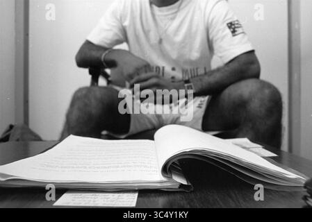 Lesley Hellings, football coach at FC De Sloterplas and the Stormvogels., Amsterdam, The Netherlands, 07-07-1992 Whizgle News, Dutch Desk, The Netherlands, 1950-2000 A person sits casually with their hands clasped, wearing a simple outfit. In the foreground, an open notebook lies on a table, displaying handwritten notes and a blank card. The scene conveys a relaxed atmosphere, suggesting a moment of contemplation or discussion. Stock Photo