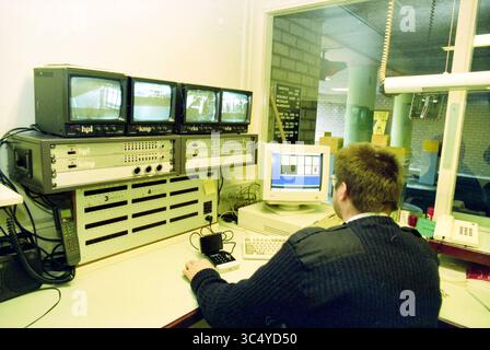 Control room Houtplein garage, Haarlem, Houtplein, The Netherlands, 23-01-1997 Whizgle News, Dutch Desk, The Netherlands, 1950-2000 A person sits at a desk, focused on a computer monitor while surrounded by multiple small screens displaying live video feeds. The workspace features various electronic devices and equipment, emphasizing a scene of surveillance or monitoring activity. Stock Photo