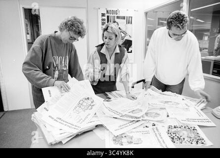 Judging Bruna's drawing on ed. Haarlems Dagblad, Haarlems Dagblad, etc. and IJmuider Courant and Koeri, Jury, 03-10-1989 Whizgle News, Dutch Desk, The Netherlands, 1950-2000 Three individuals are focused on sorting through a large stack of newspapers, collaborating on a project. Their expressions convey concentration as they sift through the materials, surrounded by a workspace filled with various publications. Stock Photo
