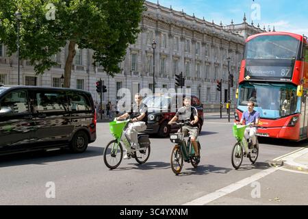 London, England, UK - 4 July 2025: People riding Lime Bikes in Whitehall in central London with taxis and a London bus in traffic Stock Photo