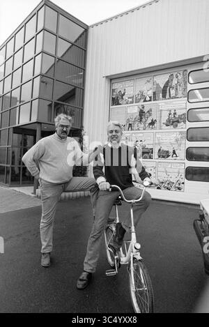 Gebr. v. Gaalen, Dubbel AA, H'lem, Haarlem, The Netherlands, 01-01-1991 Whizgle News, Dutch Desk, The Netherlands, 1950-2000 Two men pose outside a large building featuring a mural of comic strip panels. One man stands with a hand on his hip while the other sits on a bicycle, casually smiling at the camera. The clean lines of the modern architecture provide a contrasting backdrop to the playful artwork. Stock Photo
