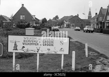 Rep. Groede, Zeeland, Villages and cities, Groede, 11-07-1984 Whizgle News, Dutch Desk, The Netherlands, 1950-2000 A welcome sign at the entrance of a quaint village, displaying greetings in multiple languages, flanked by simple houses and a glimpse of a church steeple in the background along a quiet street. Stock Photo