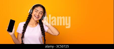 Smiling Young Woman Listening To Music Holding Smartphone Stock Photo