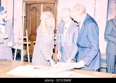 Maxima x Willem Alexander Haarlem H,lem, Haarlem, The Netherlands, 31-10-2001 Whizgle News, Dutch Desk, The Netherlands, 1950-2000 A group of individuals collaborates around a table, examining documents laid out before them. One woman, dressed in a patterned outfit, appears engaged in the discussion, while two men listen attentively. The atmosphere suggests a formal meeting or presentation. Stock Photo