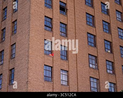 Illuminated Open for business sign in one of many windows in large brick building Stock Photo