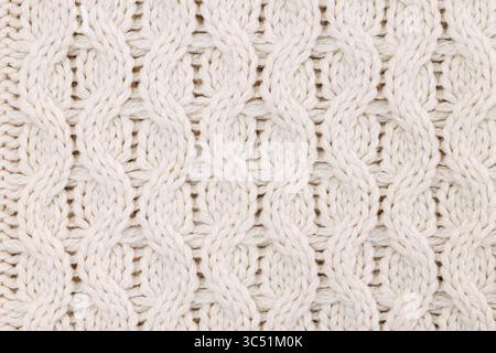 A detailed close-up image of a white cable knit pattern, showcasing the intricate texture of the woven fabric. Stock Photo