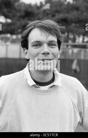 Tennis players, 00-04-1985 Whizgle News, Dutch Desk, The Netherlands, 1950-2000 A young man with tousled hair smiles warmly at the camera, dressed casually in a light sweater and collared shirt, set against a backdrop of trees and a blurred outdoor environment. Stock Photo