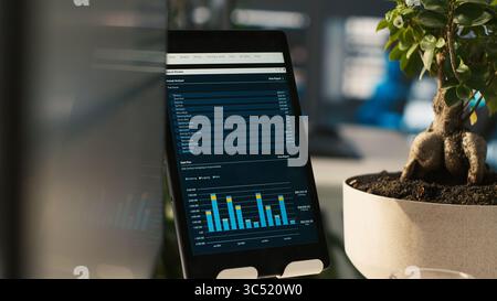 Close up of tablet screen on desk displaying financial graphs of company profits performance metrics. Data analytics on device display showing corporate business earnings KPIs Stock Photo