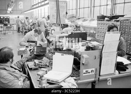 Company report NS Haarlem workshop, Railways, Haarlem, The Netherlands, 17-01-1980 Whizgle News, Dutch Desk, The Netherlands, 1950-2000 A bustling workspace filled with technicians engaged in electronic assembly and repair. Workstations are cluttered with tools, equipment, and components, while employees focus intently on their tasks amidst a backdrop of organized chaos. Stock Photo