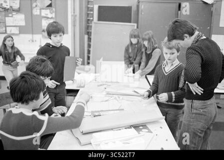 Montessori school near Kreater, Schools, 30-01-1981 Whizgle News, Dutch Desk, The Netherlands, 1950-2000 A group of children engaging in a creative project, collaborating around a table filled with various materials, including paper and model components. Some kids are focused on their work, while others observe, showcasing a lively atmosphere of teamwork and exploration in a classroom setting. Stock Photo