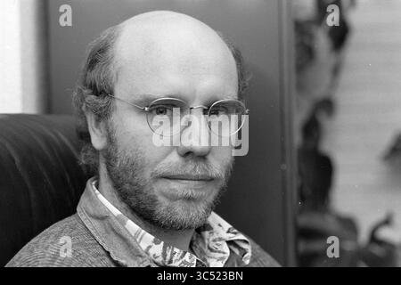 Mr. Kruup regarding WAO, H'lem, Haarlem, The Netherlands, 19-01-1995 Whizgle News, Dutch Desk, The Netherlands, 1950-2000 A man with a thoughtful expression sits comfortably, wearing round glasses and a light-patterned shirt under a cozy sweater. He has a bald head and a short beard, with a backdrop of softly blurred foliage. Stock Photo