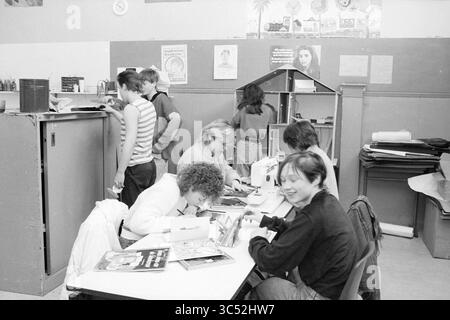 Shelter for those absent from school, Vrouwenstraat, Scholiers, Haarlem, Vrouwestraat, The Netherlands, 13-02-1985 Whizgle News, Dutch Desk, The Netherlands, 1950-2000 A diverse group of people engages in various creative activities at a large table, while others work in the background. Some are sewing, writing, or organizing materials, contributing to a lively and collaborative atmosphere in a shared workspace. Stock Photo