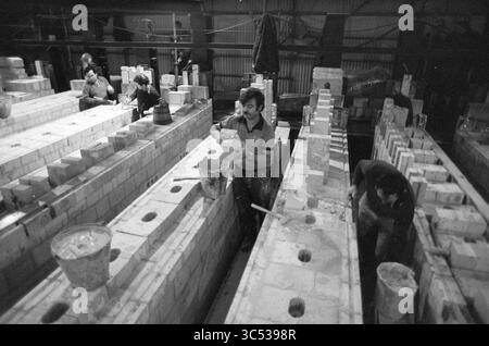 Renovation coke factory Hoogovens IJmuiden, Hoogovens, Renovation, IJmuiden, The Netherlands, 04-12-1981 Whizgle News, Dutch Desk, The Netherlands, 1950-2000 Workers are engaged in a construction site, surrounded by rows of concrete blocks and tools. One individual is carrying a bucket, while others focus on their tasks, collaborating in a busy industrial environment. The scene captures the hard work and teamwork involved in building. Stock Photo