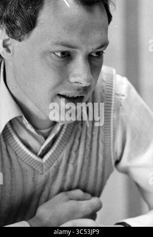 Mr Vinke, IJmuiden, Persons, IJmuiden, The Netherlands, 09-09-1982 Whizgle News, Dutch Desk, The Netherlands, 1950-2000 A young man with a focused expression engages in conversation, leaning slightly forward with his arms crossed on the table. He wears a light-colored sweater vest over a collared shirt, suggesting a thoughtful demeanor as he listens intently. Stock Photo