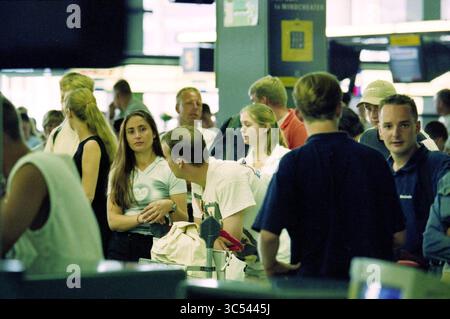 Schiphol was busy during the holidays, 12-07-1999 Whizgle News, Dutch Desk, The Netherlands, 1950-2000 A bustling scene filled with a diverse group of people engaged in conversation and activity in a public space, showcasing a blend of casual attire and various expressions as they navigate their surroundings. Stock Photo