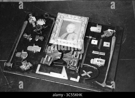 Art treasures Joh. Enschede, 08-05-1995 Whizgle News, Dutch Desk, The Netherlands, 1950-2000 A collection of various tools and objects is arranged on a flat surface, centered around a small framed portrait. The assortment includes clamps, measuring instruments, mechanical parts, and a hammer, all laid out in an organized manner, showcasing both craftsmanship and history. Stock Photo