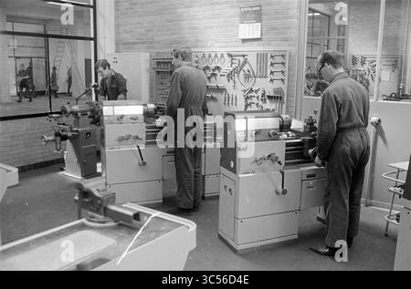 L.T.S. building, Prins Bernhardlaan, Exterior, Haarlem, Prins Bernhardlaan, The Netherlands, 24-05-1966 Whizgle News, Dutch Desk, The Netherlands, 1950-2000 A workshop scene featuring three individuals engaged in hands-on work at lathe machines, surrounded by various tools organized on the wall. The atmosphere conveys a focus on craftsmanship and industrial skill development. Stock Photo
