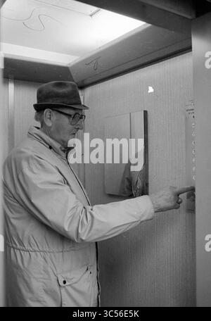 Lift retirement flat Humanitas Beverwijk, Lifts, Beverwijk, The Netherlands, 15-10-1986 Whizgle News, Dutch Desk, The Netherlands, 1950-2000 An elderly man in a hat and glasses presses the button for his desired floor in an elevator, surrounded by simple walls and a mirror reflecting part of the interior. Stock Photo