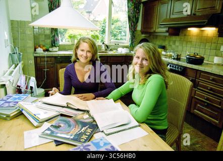 Agnes and Marije Weijers, Hoofddorp, The Netherlands, 21-05-2002 Whizgle News, Dutch Desk, The Netherlands, 1950-2000 Two individuals sit at a kitchen table, surrounded by open books and study materials. They appear engaged in a collaborative learning experience, with a warm and inviting kitchen backdrop featuring wood cabinetry and a window letting in natural light. Stock Photo