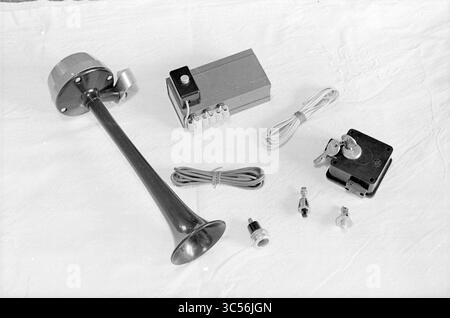 Set of burglary prevention equipment Whizgle News, Dutch Desk, The Netherlands, 1950-2000 An assortment of components including a shiny metal horn, a small electronic box with buttons and wiring, and various switches and connectors, arranged neatly on a light-colored surface. Stock Photo
