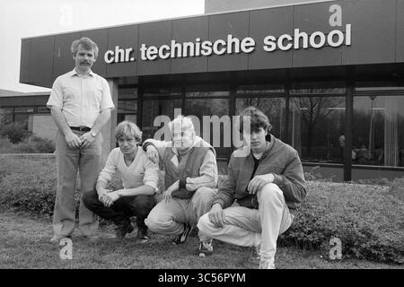 Students at technical school due to safety competition, Schools, 25-04-1983 Whizgle News, Dutch Desk, The Netherlands, 1950-2000 A group of four individuals poses outside the entrance of a technical school, showcasing a blend of casual attire. They appear to be engaged in a moment of camaraderie, with the building's name prominently displayed in the background. Stock Photo