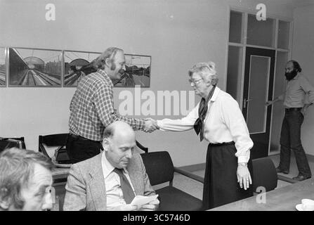 Meeting CDA - D66 - PVDA - VVD about crisis council of H'lem, Municipal Council of Haarlem, Haarlem, The Netherlands, 13-10-1980 Whizgle News, Dutch Desk, The Netherlands, 1950-2000 A group of people engages in a serious discussion around a table, while one woman extends her hand for a handshake with a man wearing a checkered shirt. Another man sits thoughtfully, and a third person stands in the background, observing the interaction. Framed images of train stations adorn the wall behind them. Stock Photo