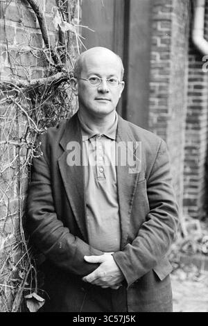 Conductor David Porselijn, 28-11-1995 Whizgle News, Dutch Desk, The Netherlands, 1950-2000 A man stands casually leaning against a brick wall, dressed in a blazer over a collared shirt. He has a thoughtful expression, with his arms crossed in front of him, while vines climb the wall behind him. Stock Photo