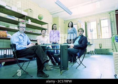 X-Ray Haarlem, Haarlem, The Netherlands, 01-04-2002 Whizgle News, Dutch Desk, The Netherlands, 1950-2000 A diverse group of five individuals gathers around a table in a spacious, minimalist room. They appear engaged and professional, with various expressions that suggest thoughtful collaboration. The environment features shelves filled with files and a globe, hinting at a creative or academic setting. Stock Photo