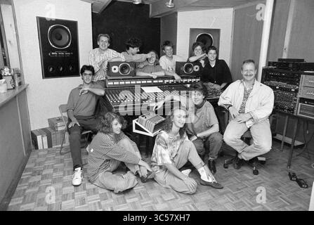 School admission. Bananas, 25-05-1990 Whizgle News, Dutch Desk, The Netherlands, 1950-2000 A lively group of young musicians and producers gathers around a large mixing console in a recording studio, showcasing a blend of playful expressions and relaxed camaraderie. The scene captures an atmosphere of creativity and collaboration, with various musical equipment in the background. Stock Photo