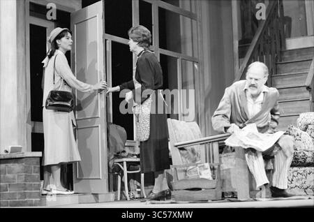 Theater diary of a Benjamin, Toneel Drogtrop, 26-09-1984 Whizgle News, Dutch Desk, The Netherlands, 1950-2000 A woman stands at the doorway, engaging in conversation with another woman, while a man sits in a chair nearby, reading a newspaper. The setting suggests a domestic scene with a staircase in the background and a cozy living area. Stock Photo