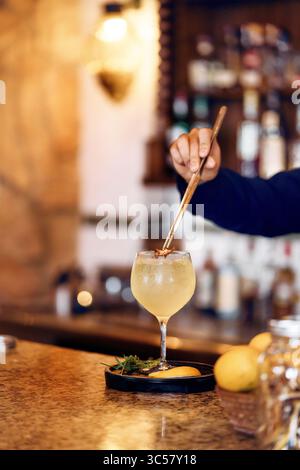 Professional bartender pouring craft cocktail into elegant coupe glass. Premium bar service and mixology skills in sophisticated restaurant setting. Stock Photo