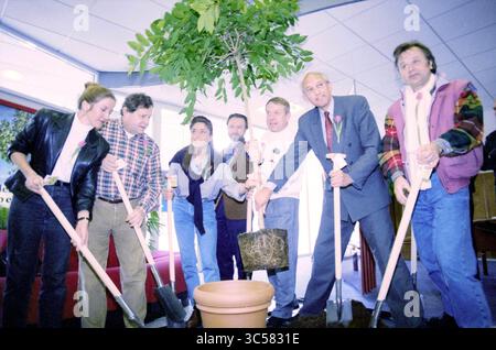 First ticket of the National Green Fund Lottery, 20-03-1995 Whizgle News, Dutch Desk, The Netherlands, 1950-2000 A diverse group of individuals, smiling and holding shovels, gathers around a large potted plant, ready to engage in planting. The scene conveys a sense of teamwork and enthusiasm for nurturing nature. Stock Photo