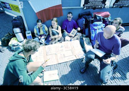 Polish students, Grote Markt, Haarlem, Grote Markt, The Netherlands, 17-08-2000 Whizgle News, Dutch Desk, The Netherlands, 1950-2000 A group of people sits together on the ground, engaged in sketching and drawing on various papers spread out before them. They appear to be sharing ideas and collaborating, surrounded by backpacks and art supplies in a vibrant, lively atmosphere. Stock Photo