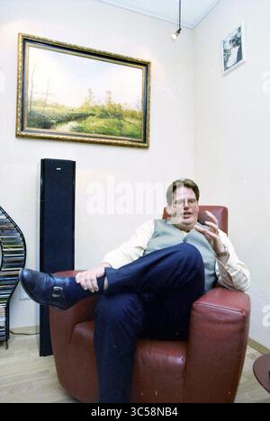 Mr. van Dijk, national Orange Association, Hoofddorp, The Netherlands, 02-03-1997 Whizgle News, Dutch Desk, The Netherlands, 1950-2000 A man in a tailored vest sits comfortably in a cozy armchair, gesturing as he speaks. Behind him, a serene landscape painting adds a touch of elegance to the room, alongside a modern speaker and a bookshelf filled with music CDs. Stock Photo