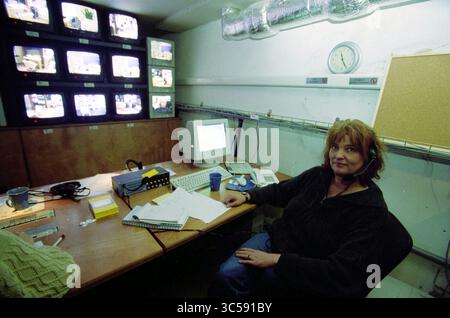 Kitty Verheul, Amsterdam, Amsterdam, The Netherlands, 09-01-2001 Whizgle News, Dutch Desk, The Netherlands, 1950-2000 A person sits at a control station surrounded by multiple monitors displaying live feeds, with a computer, paperwork, and personal items scattered on the desk, creating a focused atmosphere of surveillance and management. Stock Photo
