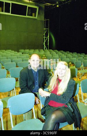 Theater E.C.L., Haarlem, The Netherlands, 25-11-2001 Whizgle News, Dutch Desk, The Netherlands, 1950-2000 A man and a woman sit together in an auditorium filled with empty chairs, with the woman smiling and the man looking directly at the camera. The stage in the background signifies an upcoming event, creating a sense of anticipation. Stock Photo