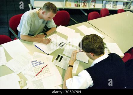 Studying students, Haarlem University of Applied Sciences, Haarlem, The Netherlands, 29-06-1999 Whizgle News, Dutch Desk, The Netherlands, 1950-2000 Two individuals are seated at a table cluttered with papers and a book titled "Small Business Economics." They appear to be engaged in focused study or discussion, taking notes and reviewing materials related to their academic or business endeavors. Stock Photo