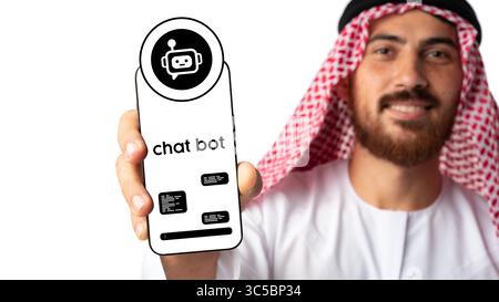 Man in traditional attire showcasing a smartphone with a chatbot interface in a modern setting Stock Photo