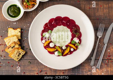Beet carpaccio with orange slices, fresh greens and cream dots Stock Photo