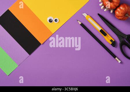 Items for paper crafts in Halloween colors. Pencil, glue, eraser, knife, scissors and colored pieces of paper. Stock Photo