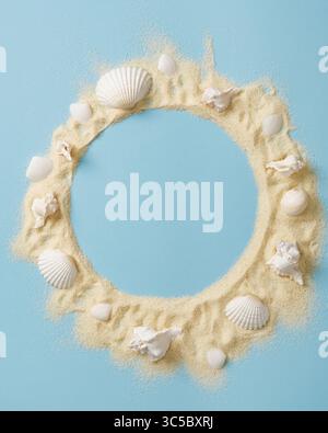 Round frame of white sand and various white shells on a bright blue background. A place for your text. Stock Photo