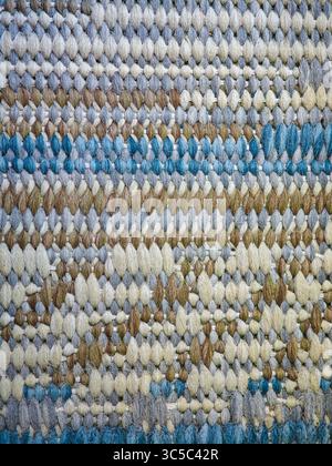 Close-up of a multicolored woven rug with blue, beige, and brown tones, showing detailed texture and pattern. Stock Photo
