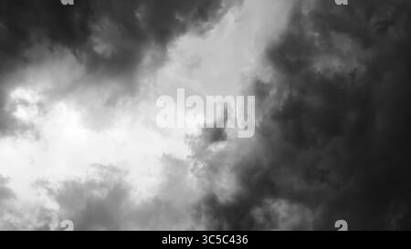 Black and white image of dramatic storm clouds swirling in the sky, creating a high-contrast, moody atmosphere. Stock Photo