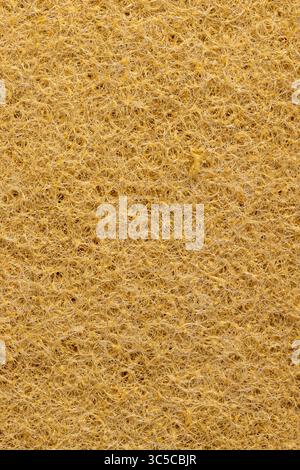 rigid fabric for washing large dirt on objects, glued and tightly intertwined synthetic sand-colored threads on a sponge that is used for cleaning and Stock Photo