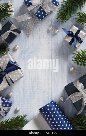 A frame made of fir branches, gift boxes, ribbons, and wrapping paper in blue and silver colors. Space for your text. Stock Photo