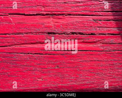 Horizontal wooden planks painted in a vibrant, slightly faded red hue, showing cracks and textures, creating a rustic and colorful backdrop Stock Photo