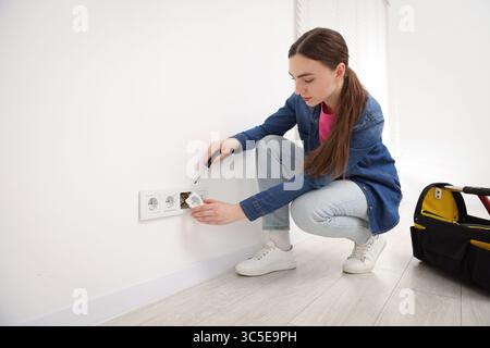 Woman with screwdriver installing new socket at home Stock Photo
