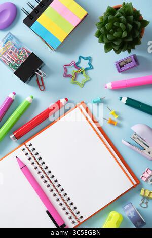 Stationery background with open notepad, felt-tip pens, paper clips, clipboards, paper clips, sticky notes and pins. Light blue background. Stock Photo