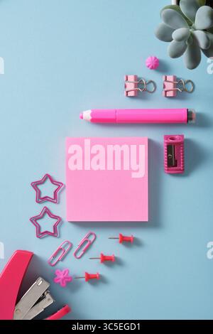 Card with pink sticky notes and office supplies stapler, paper clips, sharpener, eraser, pins. Place for text. Stock Photo
