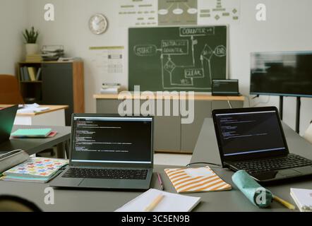 Two Laptops Displaying Programming Code in Classroom during Lesson Stock Photo